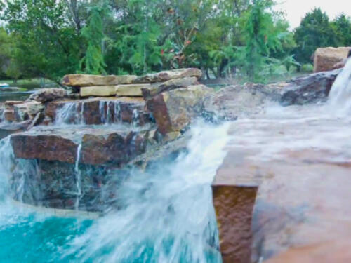 swimming pool waterfall with boulders
